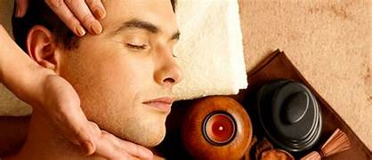 Man enjoying a peaceful facial and head massage at Lotus Men’s Spa in Anantapur with soothing candles and herbal spa setup.